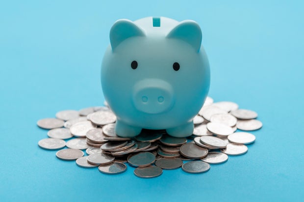 Piggy bank and coin on light blue background for money savings. Earning interest on savings. Growing your wealth and saving money concept 