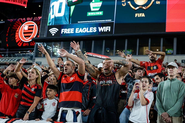 Fans of Flamengo CR raise their arms as they cheer on their team at the Linc 