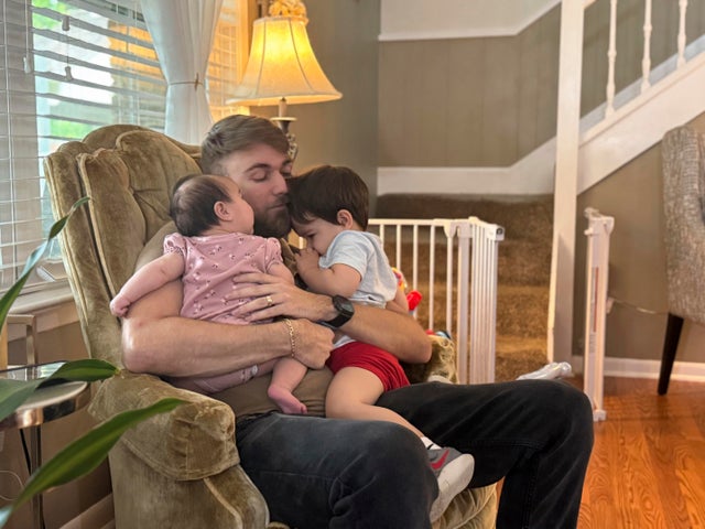 U.S. Marine Corps veteran Adrian Clouatre holds his 3-month-old daughter Lyn and his nearly 2-year-old son Noah at their home in Baton Rouge, Louisiana, June 17, 2025. 