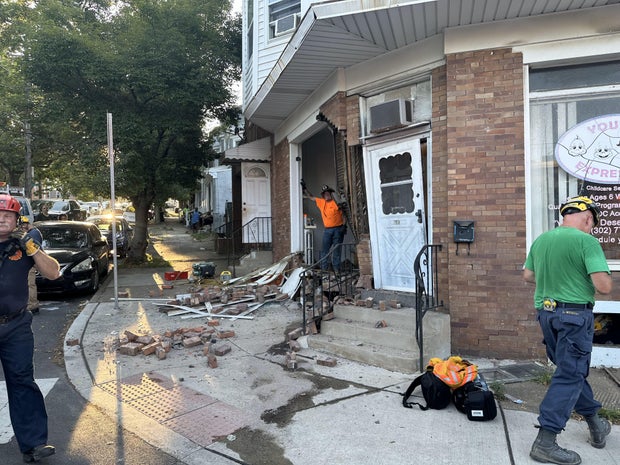 The exterior wall of a brick building that houses a day care in Wilmington is damaged, bricks and debris are seen on the sidewalk 