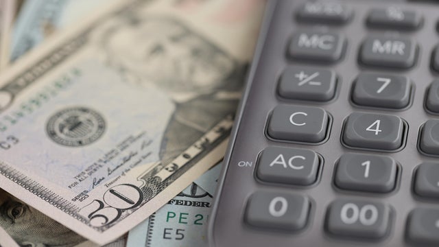 Gray calculator lying on dollar bills closeup 