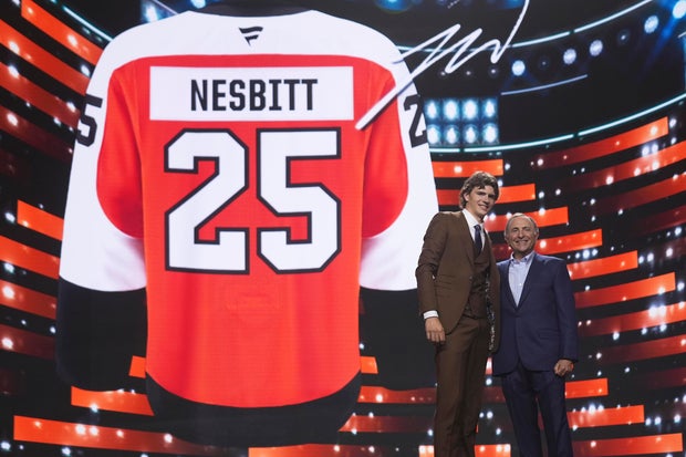Jack Nesbitt, left, stands with NHL commissioner Gary Bettman after being drafted by the Philadelphia Flyers, a picture of a Nesbitt Flyers jersey is in the background 