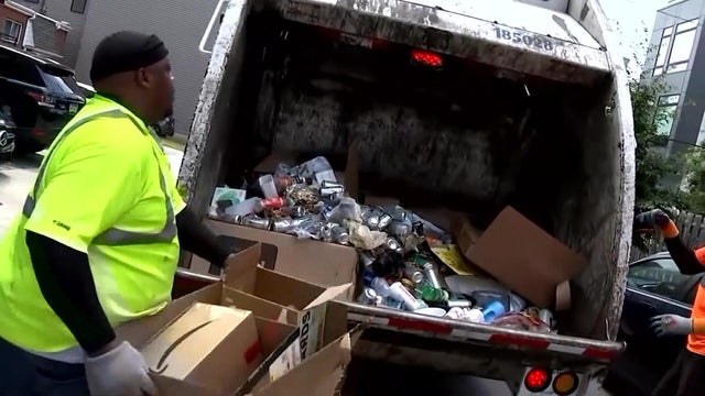 A sanitation worker throws boxes into a trash truck in Philadelphia 