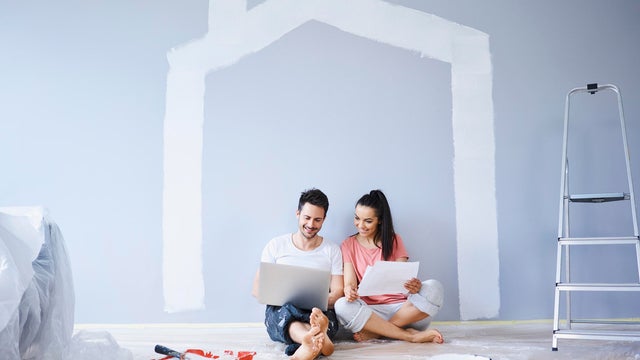 Couple sitting in new apartment using laptop 