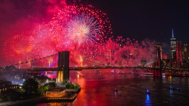 People watch as fireworks light up the sky above the Brooklyn Bridge during Macy's 4th of July fireworks show on July 4, 2025 in New York City. 