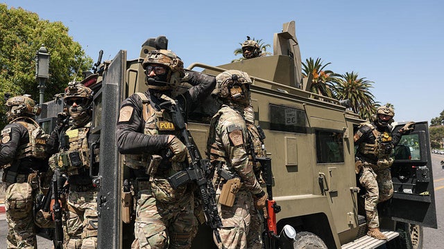 Federal agents with Customs and Border Protection ride on an armored vehicle on Wilshire Boulevard near MacArthur Park in Los Angeles, California, on July 7, 2025. 