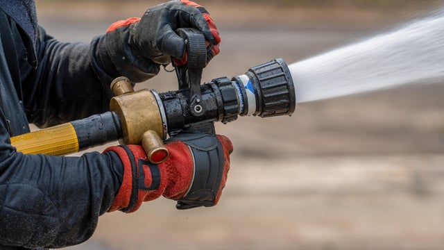 Close up hands of firefighter spraying high pressure water to fire. 