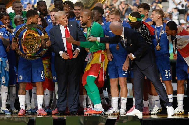 FIFA President Gianni Infantino (R) attempts to direct U.S. President Donald Trump away from the celebrating Chelsea footballers after they won the final match of the FIFA Club World Cup at MetLife Stadium on July 13, 2025 in East Rutherford, New Jersey. 