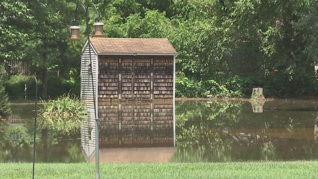 A small shed is seen in a flooded yard 