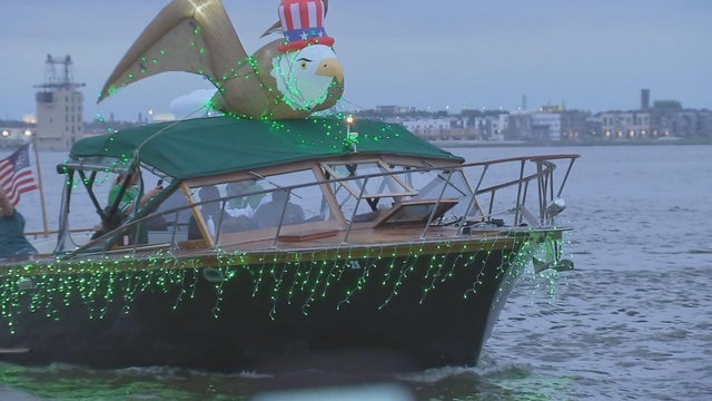 A boat with green lights and an inflatable eagle on top cruises in the Delaware River off the coast of Philadelphia 