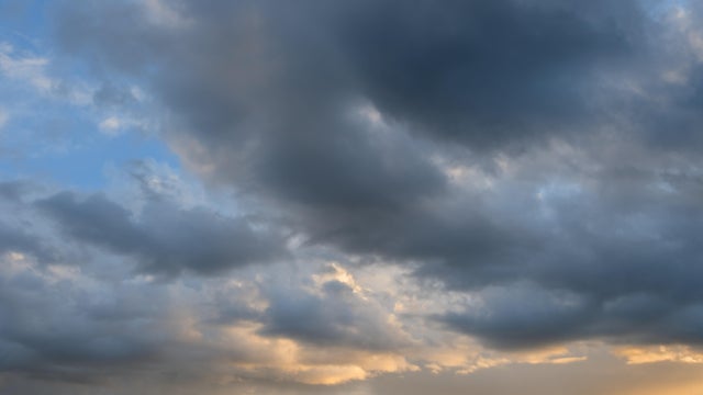 Cumulus sunset clouds with sun setting down 