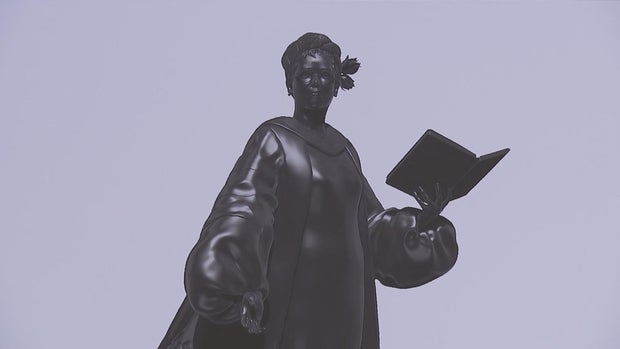A photo of the rendering of the statue, Alexander is holding a book 