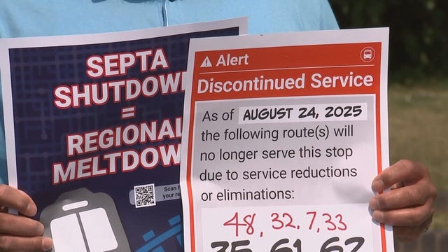 Someone holds a poster alerting riders about discontinued SEPTA service on August 24 and another that says SEPTA shutdown equals regional meltdown 