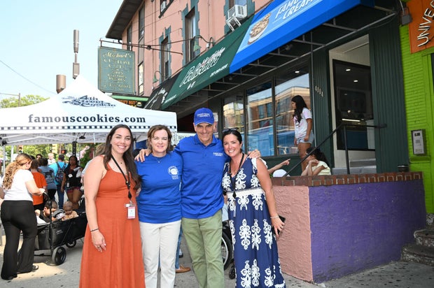 Four people smile for a photo outside the shop
