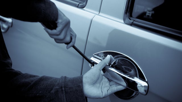 close-up of mans hands using screwdriver to break into car 