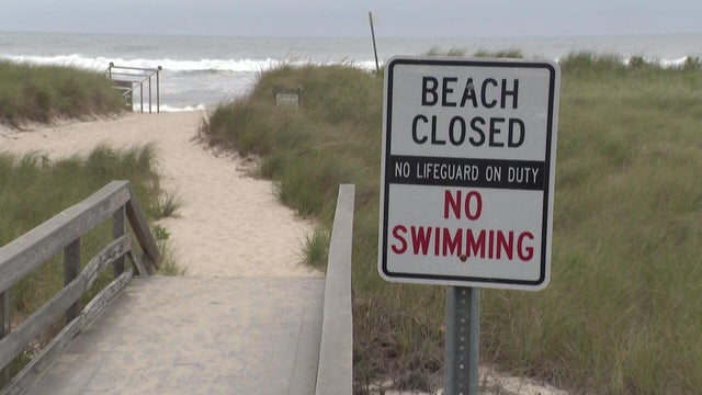 "Beach closed, no lifeguard on duty, no swimming" sign at beach entrance 