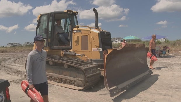 Lifeguards and a construction vehicle are seen on the beach in Strathmere 