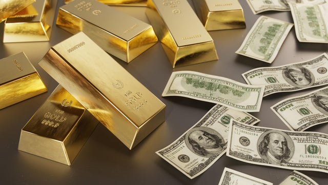 Gold bars and US dollar bills on dark background 