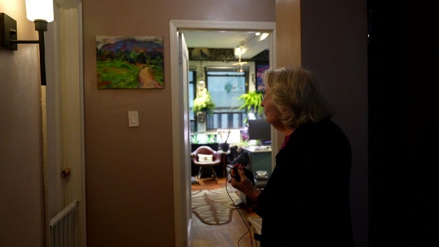 Barbara Quart looks at one of her paintings hanging in a home 