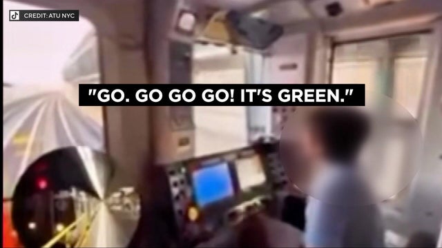 A child with their face blurred appears to be behind the controls of a running subway train. 