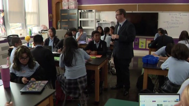 Catholic school students listen to a teacher inside a classroom 
