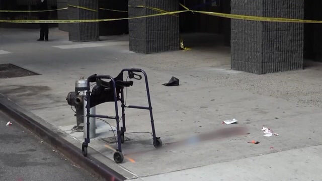 A walker is seen on a sidewalk blocked off by crime scene tape. 