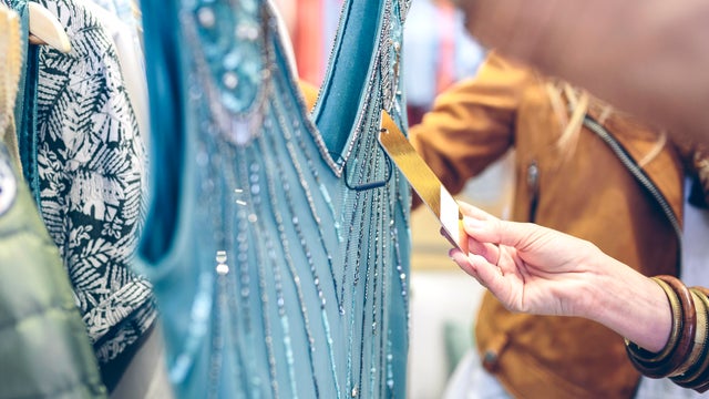 Close-up of woman checking price tag of a dress in a boutique 