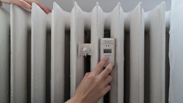 Young woman near the home radiator with temperature sensor 
