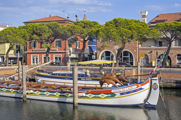 Traditional wooden boat docked in canal in the city Caorle, coastal town in the Metropolitan City of Venice, Veneto, Northern Italy 