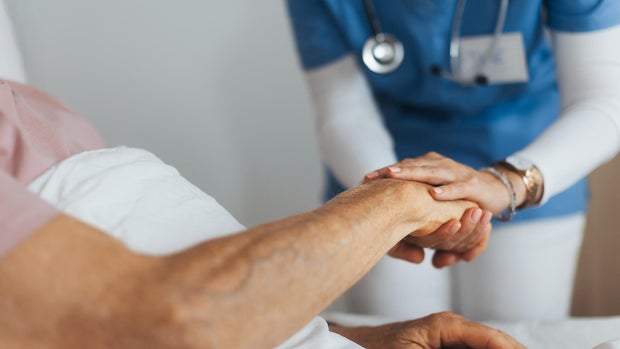 Close-up of caregiver holding senior client hand. Support from nurse to patient, taking care of elderly man in hospital. Emotional support and care in healthcare. 