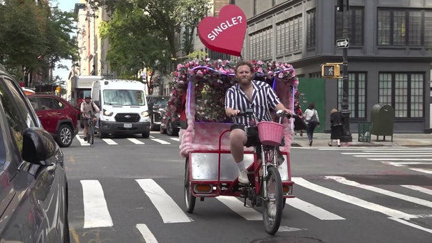 Man riding a pedicab with a large heart balloon with the word "Single?" on it 