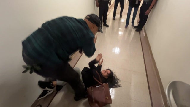 A man crouching over a woman on the floor in a hallway 