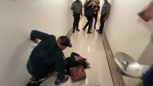 A man crouching over a woman on the floor in a hallway 