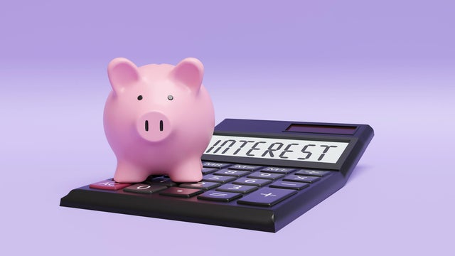 Pink piggy bank standing on a calculator on purple background. Illustration of the concept of interest rate of deposit savings 