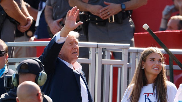 President Trump waves to the crowd on the 1st tee as his granddaughter Kai Madison Trump looks on at the Ryder Cup at Bethpage Black Golf Course in Farmingdale, New York, Sept. 26, 2025. 