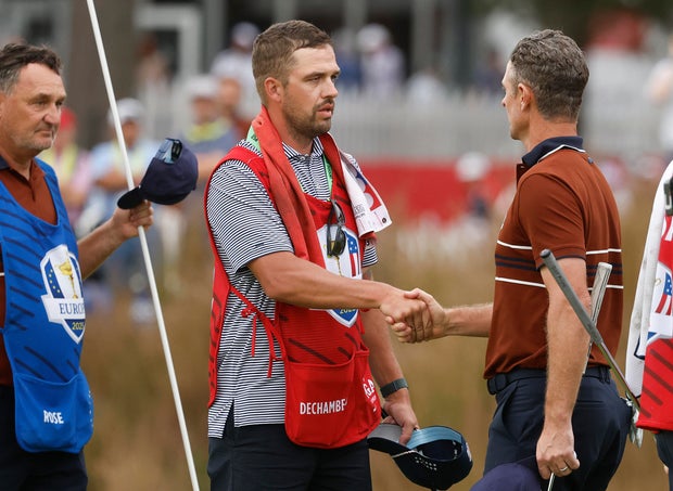 Greg Bodine, caddie for Bryson DeChambeau of Team United States, shakes hands with Justin Rose of Team Europe on the 16th hole green 