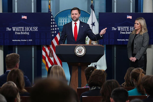 Vice President JD Vance speaks as White House Press Secretary Karoline Leavitt looks on during a press briefing at the White House in Washington, D.C., on Oct. 1, 2025. 