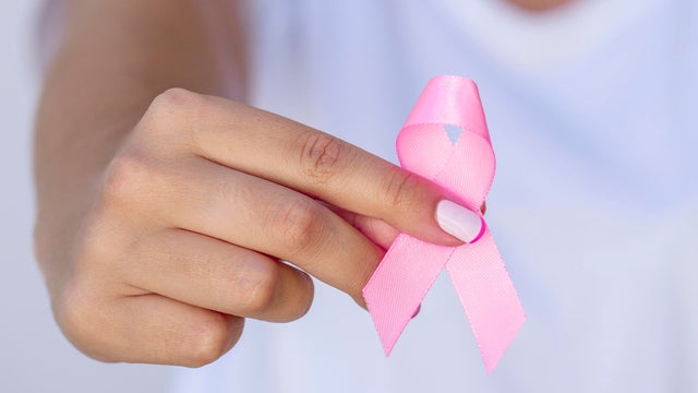 Breast cancer symbol pink ribbon in tender female hands. 