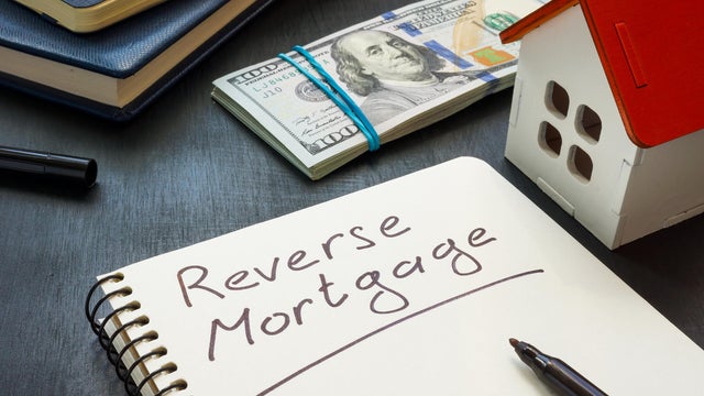 Notepad with the inscription Reverse mortgage, house model and money. 