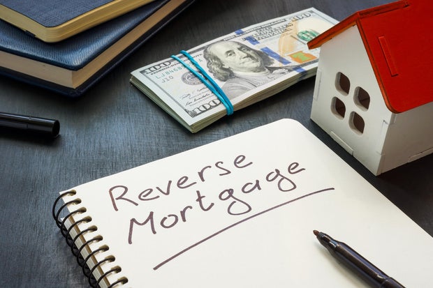 Notepad with the inscription Reverse mortgage, house model and money. 