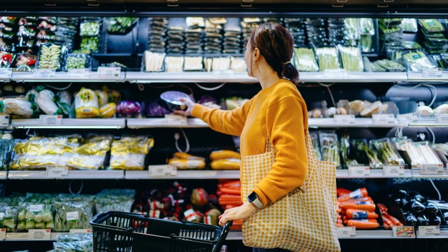 Young Asian woman with shopping cart, carrying a reusable shopping bag, shopping for fresh organic fruits and vegetables in supermarket. Environmentally friendly concept. Zero waste and plastic free. Eco friendly shopping. Sustainable living lifestyle 