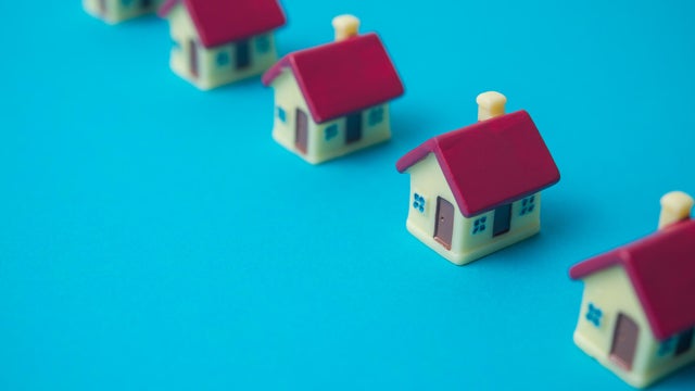 Row of small houses on blue background copy space. 