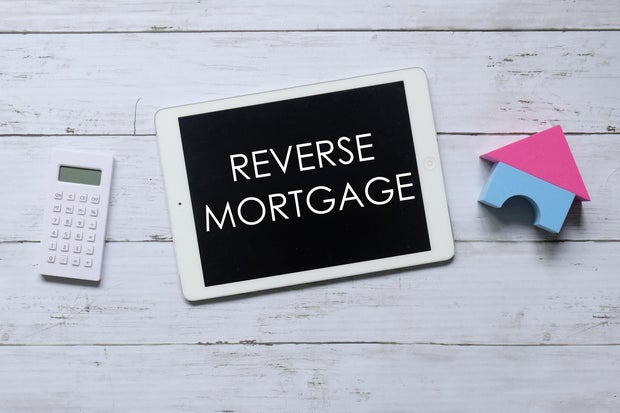 Top view of calculator,house model and tablet written with REVERSE MORTGAGE. Business and finance concept.