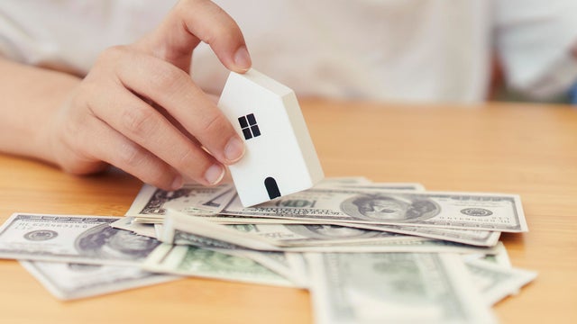 Real estate concept with a hand holding a small house, a family, and copyspace 