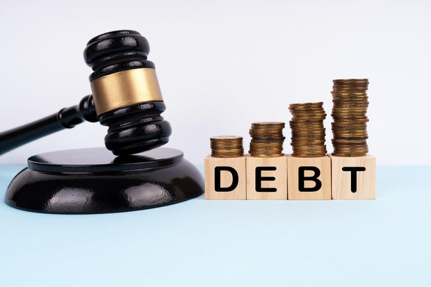 Gavel, coins stacks and wood blocks with DEBT written on them. Finance and law concept 