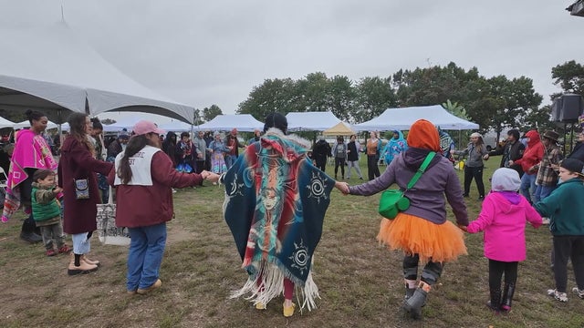 People hold hands during a traditional dance at a celebration of Indigenous Peoples Day at Penn Treaty Park in Philly 