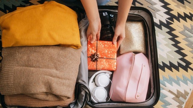 Unrecognizable woman carefully puts a gift in a suitcase 