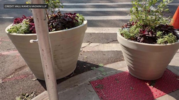 Planters block the curb cut on a sidewalk in New York City 