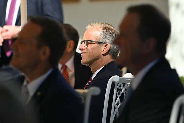 Senate Majority Leader John Thune listens to President Trump speak at a lunch in the Rose Garden of the White House on Oct. 21, 2025.