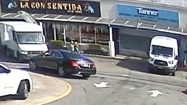 Black sedan and an individual taking a Frenchie outside restaurant